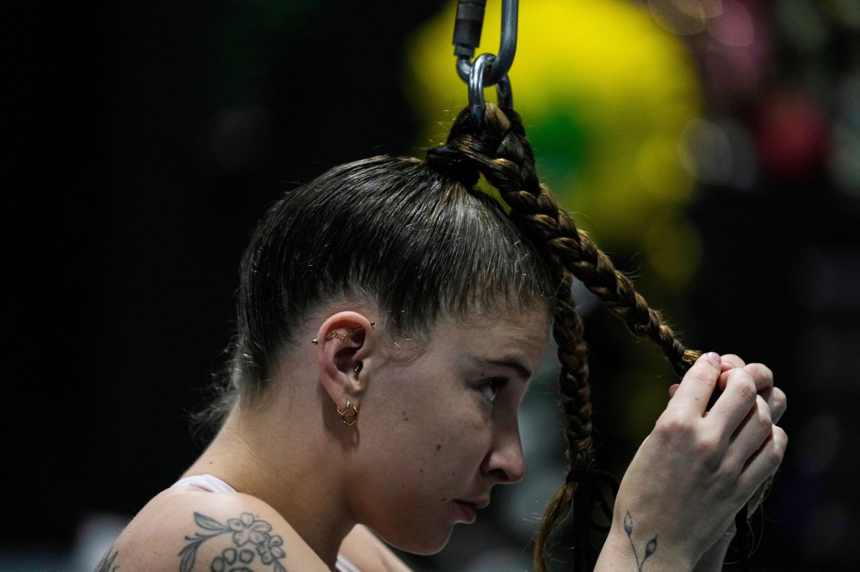 Megan Nielsen braids her hair while attached to a five-meter rope during a rehearsal at The Cirk.