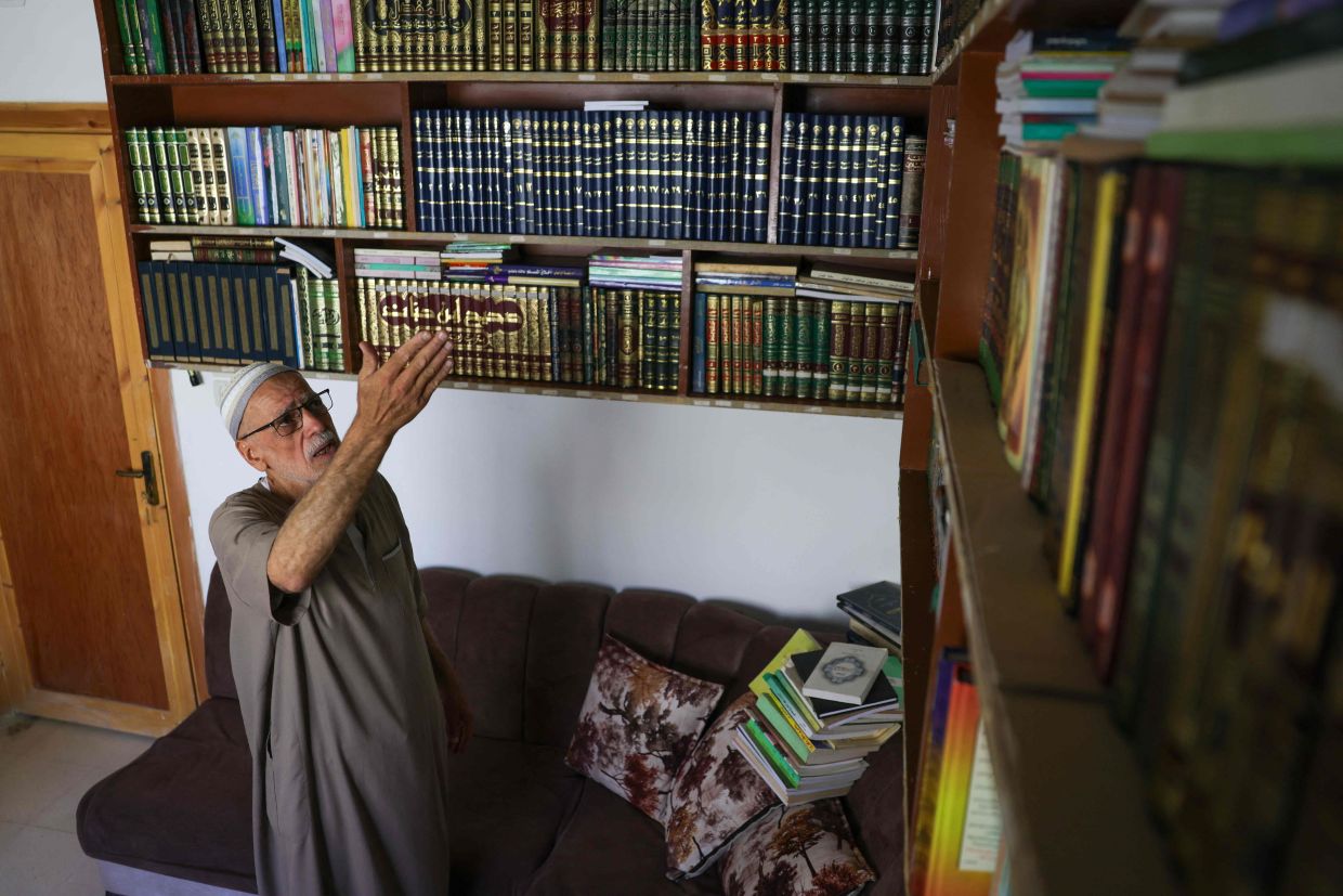 Mustafa Khaled Alwan, a 72-year-old Syrian man, poses for a picture surrounded by his books.