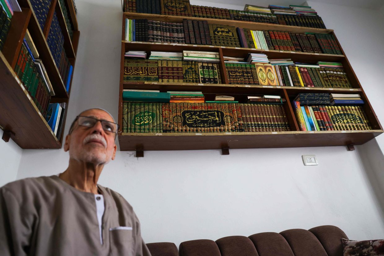 Mustafa Khaled Alwan, a 72-year-old Syrian man, poses for a picture surrounded by his books.