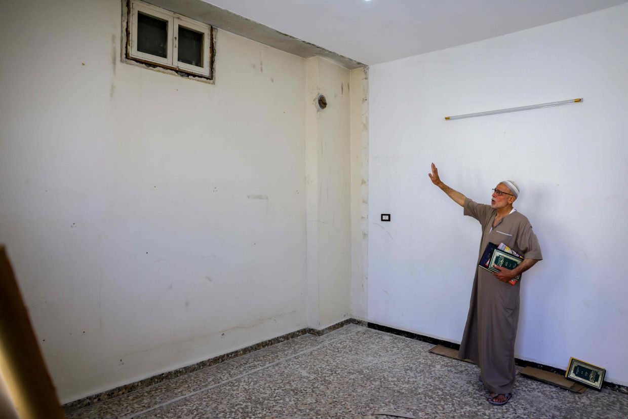Mustafa Khaled Alwan, a 72-year-old Syrian man, points at what was a false wall where he hid his books for 15 years at the start of the uprising against longtime Syrian ruler Bashar al-Assad.