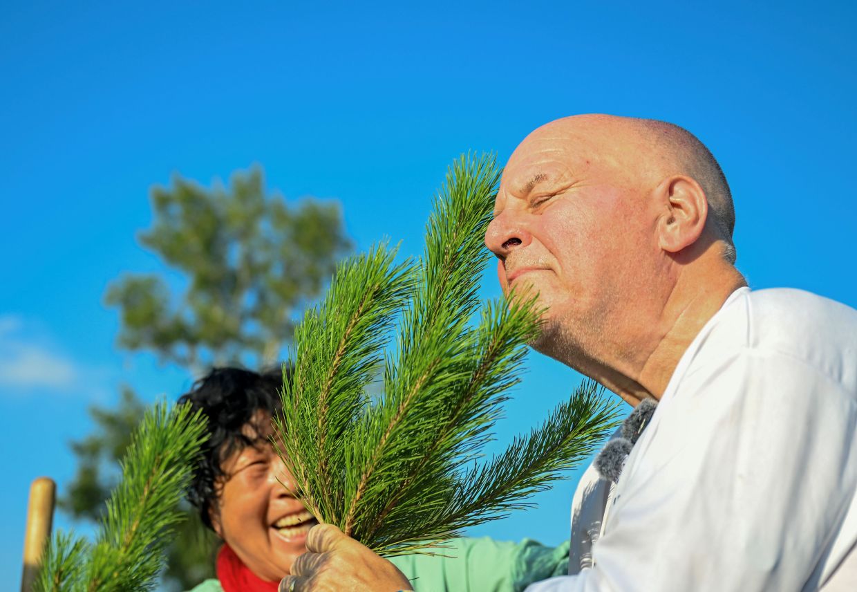 Ronald Sakolsky (right) sniffs a sapling after planting it with Yin Yuzhen in the Maowusu Sandy Land in north China's Inner Mongolia Autonomous Region, Aug. 24, 2026. — Xinhua/Lian Zhen