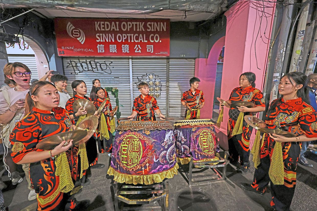 Left: A lion dance percussion team at the ready to play along the sidewalk, while the troupe performs on the street.