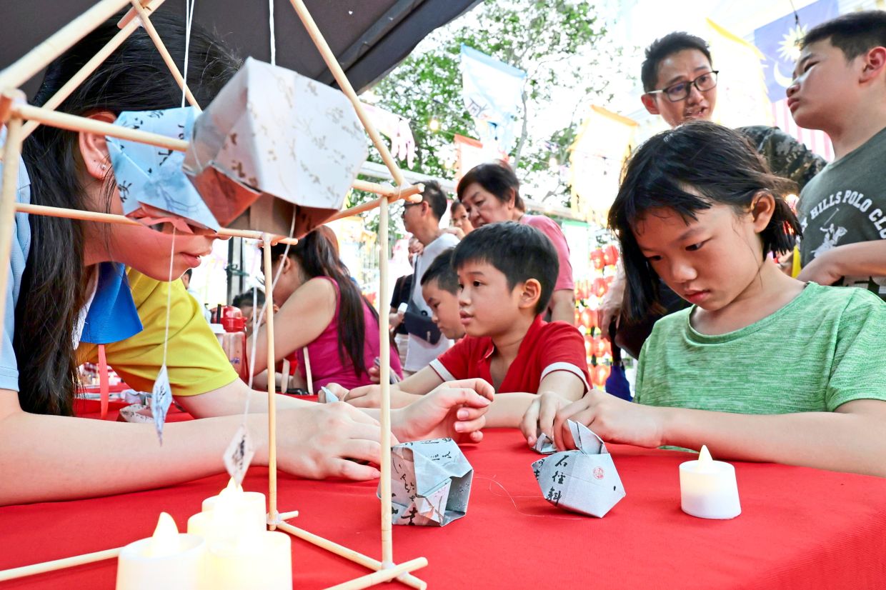 Xin Nee (in green) folding a paper into a delicate rabbit lantern at one of the many activity booths at the festival.