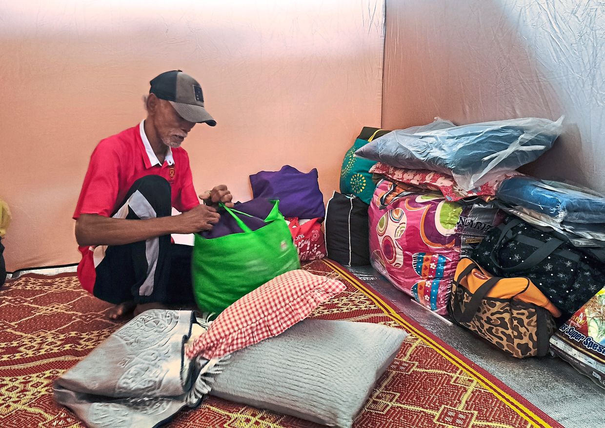 Mohd Faudzi sorting out his belongings inside a pop-up tent at the Desa Baiduri Community Hall.