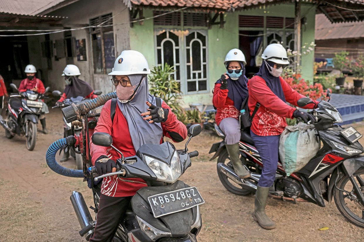 Guardians of the forest: Members of The Power of Mama carrying a water pump on a motorcycle as they prepare to extinguish a wildfire in a peatland area in Sungai Awan Kiri, Ketapang regency, West Kalimantan.— Reuters