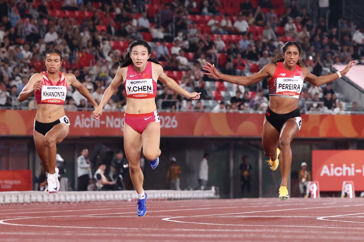 China's Chen Yujie (C) and Singapore's Veronica Pereira Shanti (R) cross the finish line in the women's 100m final. - AFP