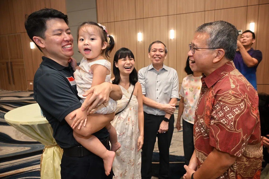 Law Minister Edwin Tong (right) with fingerprint specialist Yong Heng Wei (left) and his family at the welcome-home reception on Sept 26. - Photo: ST