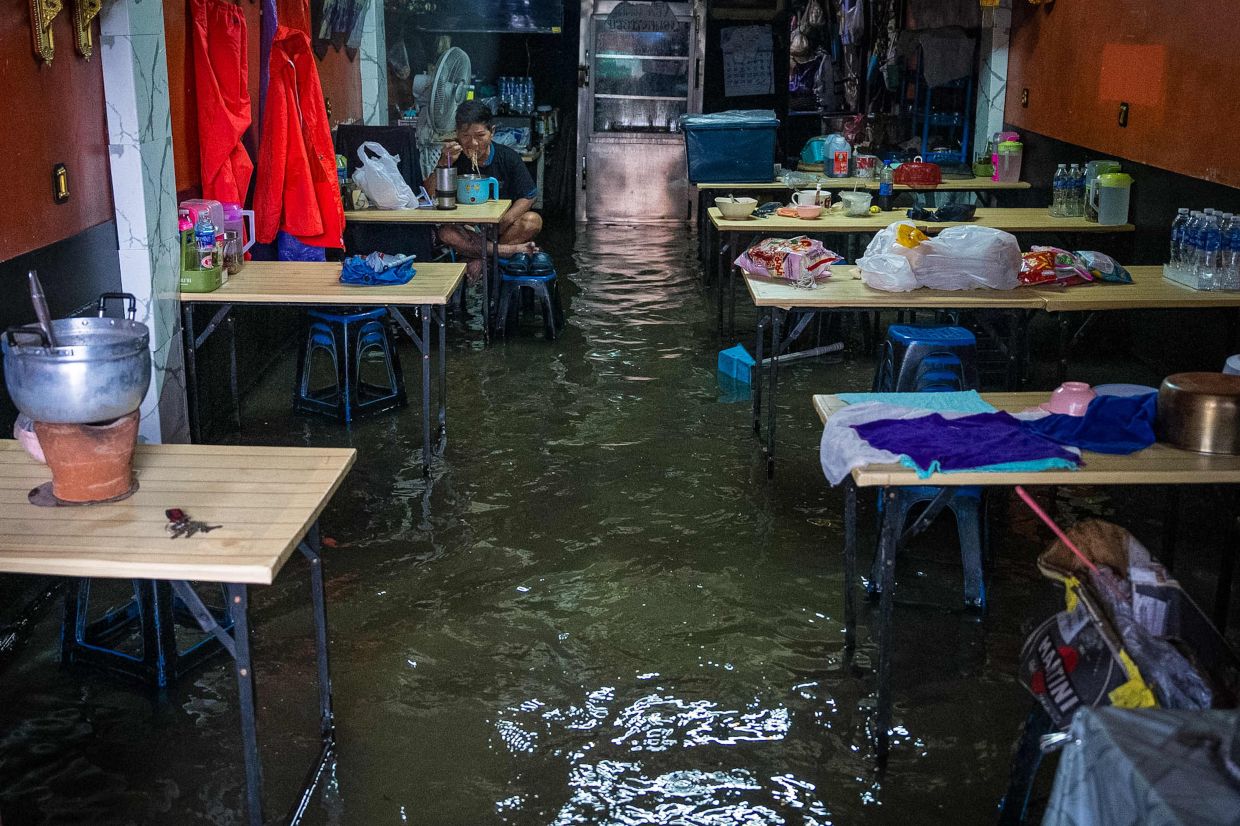 A man eats foot in a restaurant submerged in flood waters after heavy rain in Bangkok on September 26, 2026. Bangkok authorities declared a flood disaster across the Thai capital on September 26 after almost 48 hours of heavy rain left canals full, roads submerged and residents knee-deep in water. - Photo: AFP