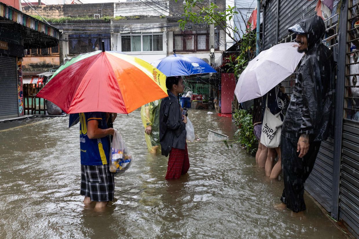 Residents stand in floodwater while queueing to buy goods from a shop in the Bang Bua district of Bangkok on September 26, 2026. Bangkok authorities declared a flood disaster across the Thai capital after almost 48 hours of heavy rain left canals full, roads submerged and residents wading through deep water. - Photo: AFP