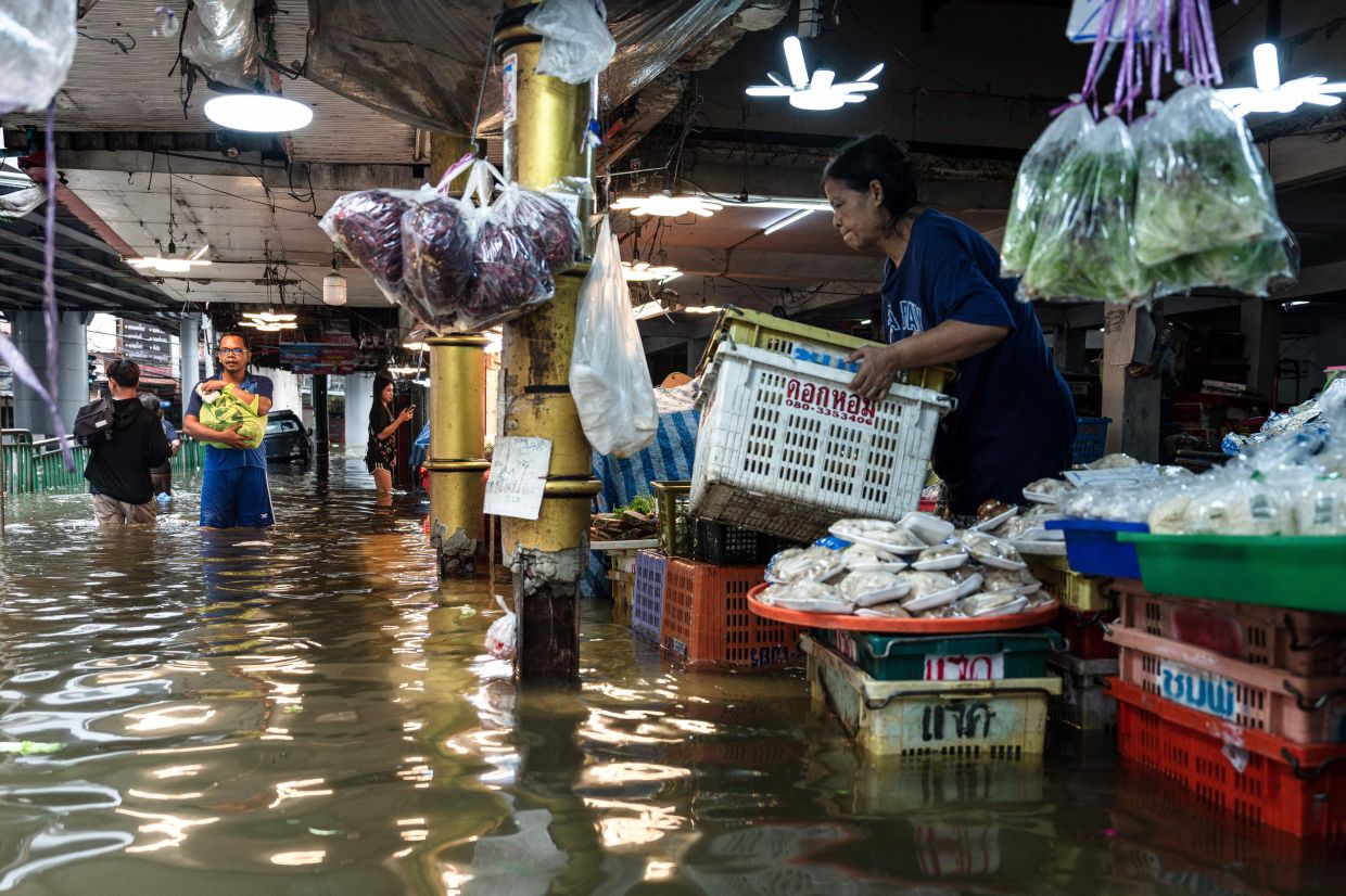 People wade through flood waters next to food stalls in the Bang Kapi district of Bangkok on Sept 27, 2026. Thousands of Bangkok residents awoke in shelters on Sept 27 after flooding triggered by days of heavy rain in the Thai capital inundated homes and roads, with some starting to dry out their homes and belongings. - Photo: AFP