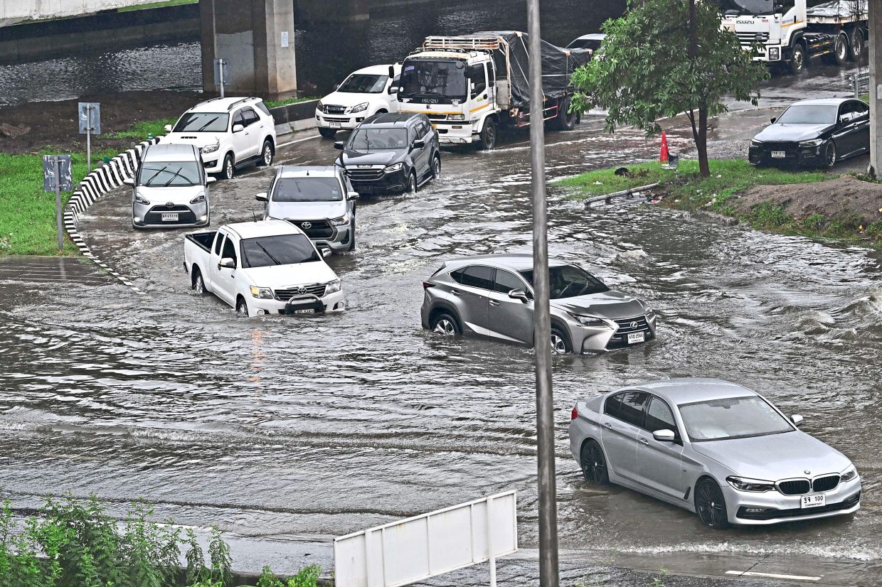 In a jam: Vehicles driving through floodwaters in Bangkok. — Xinhua