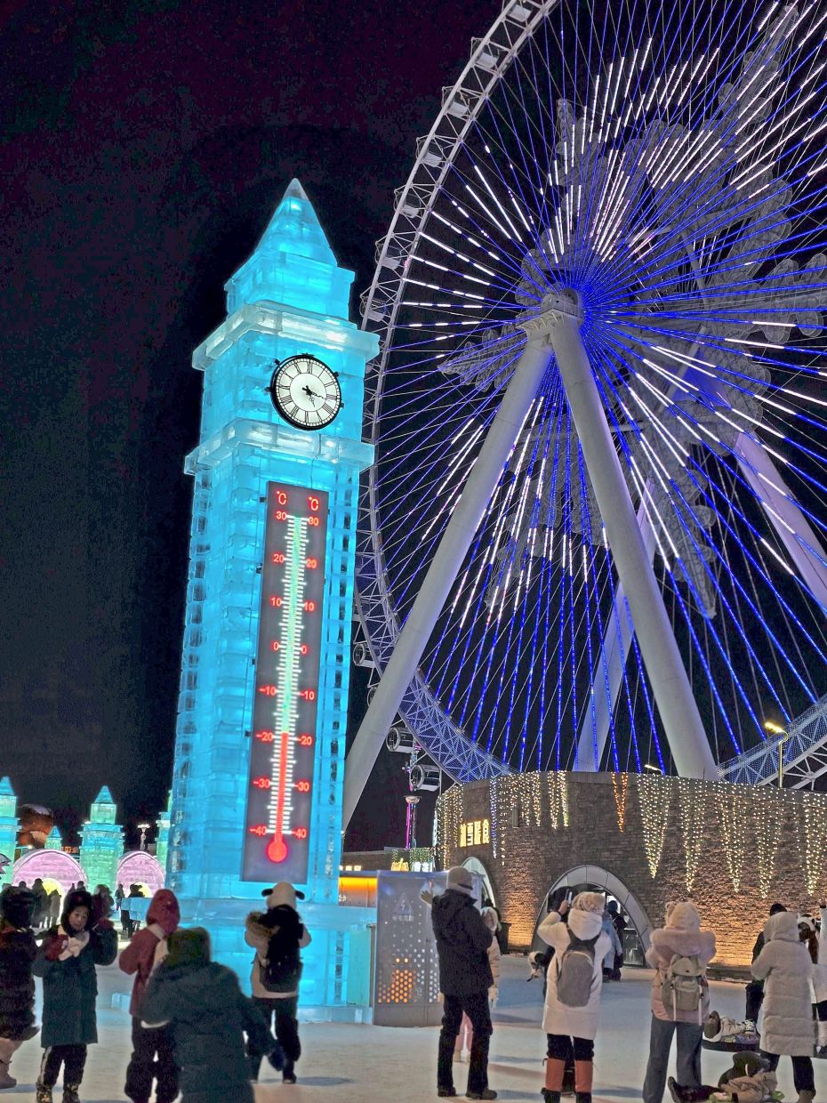 A clock tower with a thermometer that’s mainly made from ice stood next to the Ferris wheel at the Harbin Ice and Snow World.