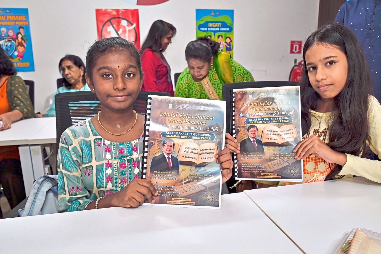 Participants of the free Tamil language programme showing their learning materials.