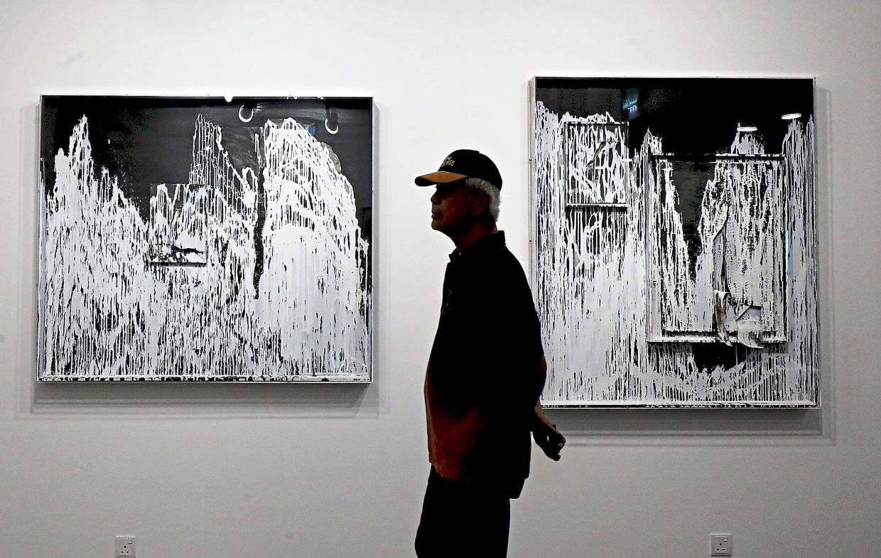 A visitor walks past Yeoh’s latest abstract works on wooden panels, including (from left) 'In Plain Sight' and 'Nothing Underneath Is Still', at the 'Shan Shui As Camouflage' exhibition in KL.