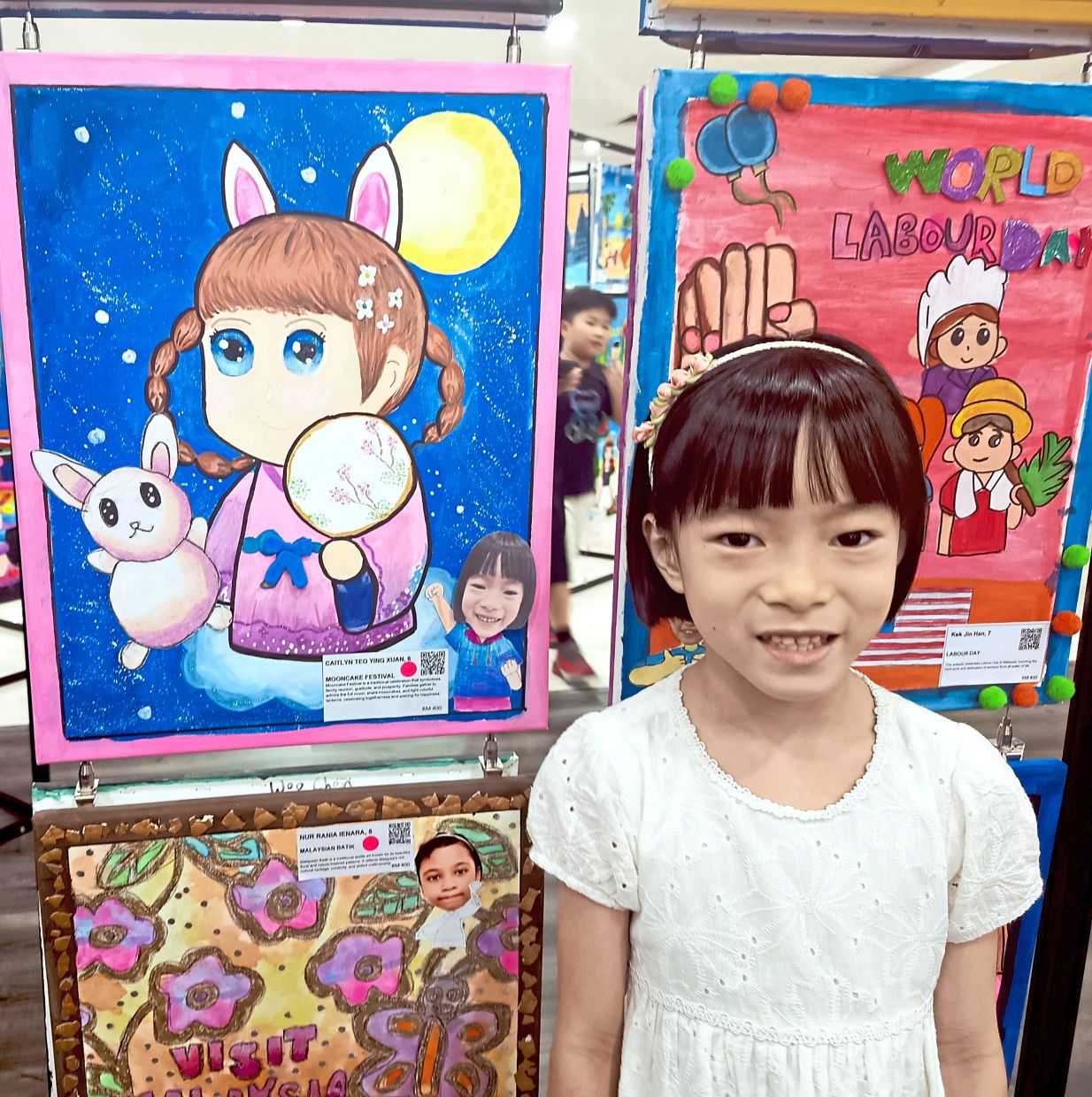 Caitlyn Teo standing next to the panting she contributed for the art exhibition.