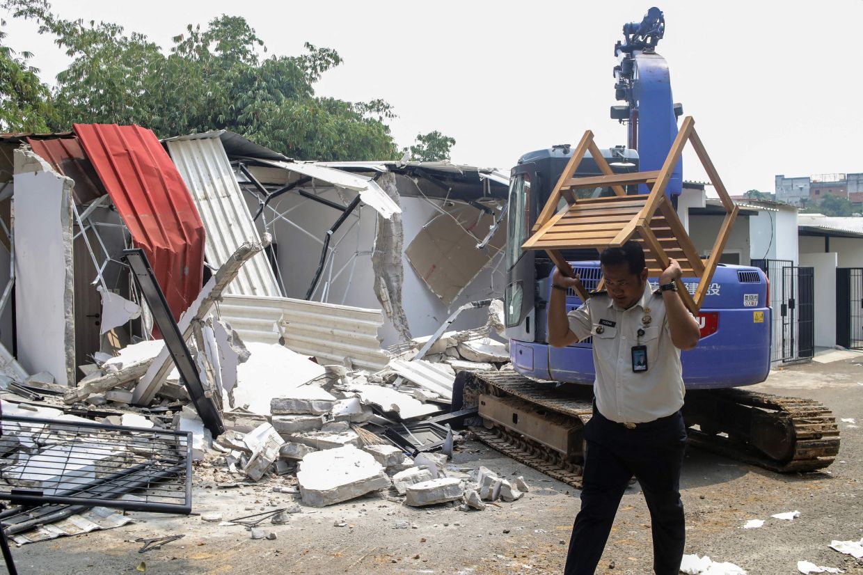 Footage showed the excavator tearing through the white-painted buildings as roofs and ceiling frames collapsed. - AFP