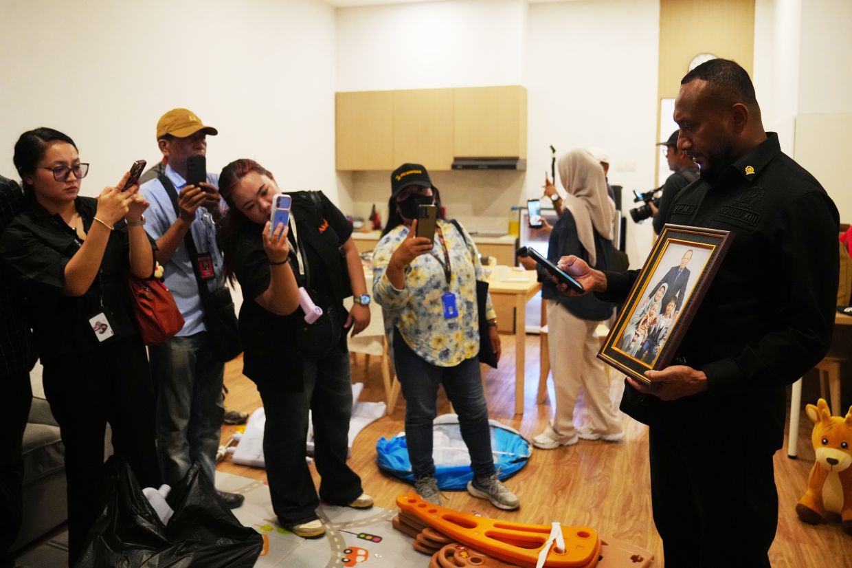 A lawmaker showing journalists a framed family photograph at the controversial luxury compound on Sept 30, 2026. - AP