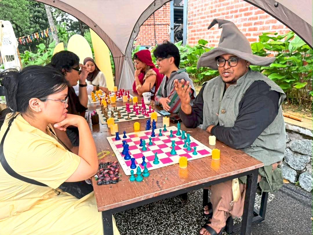 Visitors, some dressed in fancy costumes, taking part in chess challenges by Chess MTS and Magic: The Gathering at TMIYC Johor Baru..