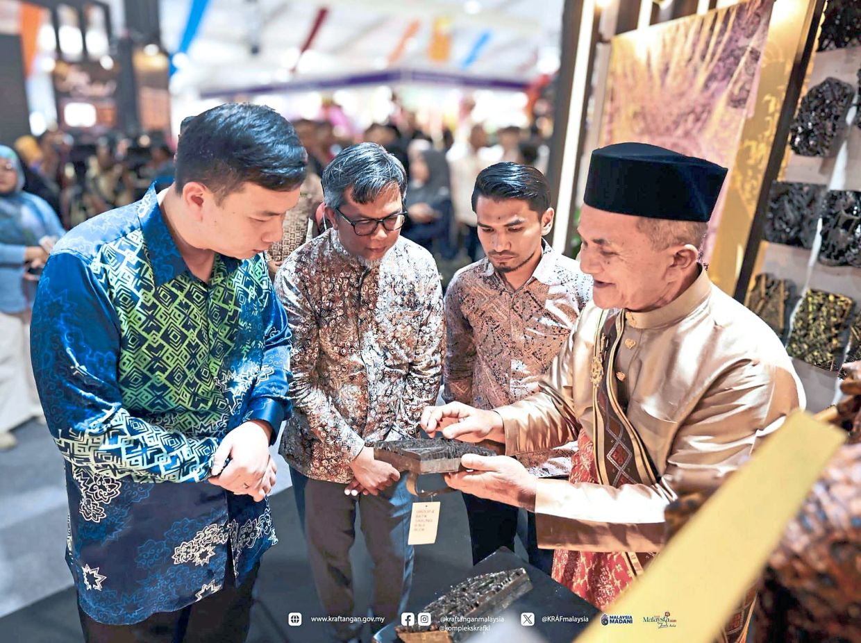 Ibrahim (right) showing Chiew (left) a batik block during the craft fair.
