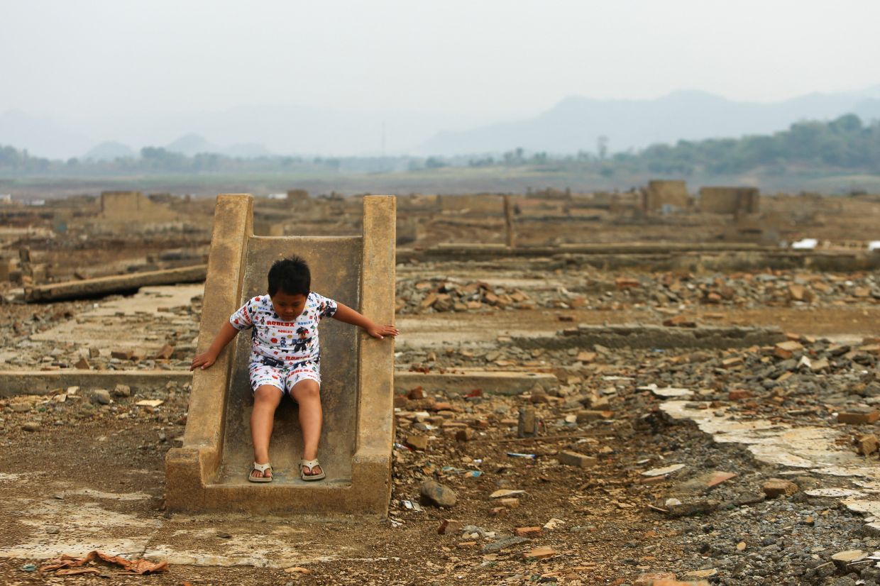 A boy playing on an exposed slide as water levels recede at Jatigede Reservoir amid drought during the dry season in Sumedang Regency, West Java province, Indonesia, on Oct 1. - Reuters