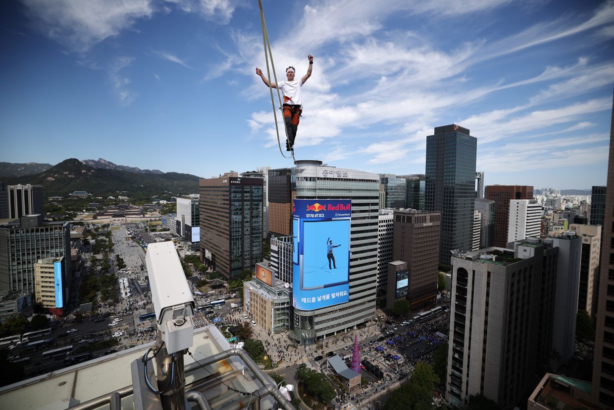 Estonian slackliner Jaan Roose performing on a slackline during South Korea's first urban highline crossing event which is on a 160-metre-long and suspended 120m above the ground, in central Seoul on Oct 1, 2026. - AP