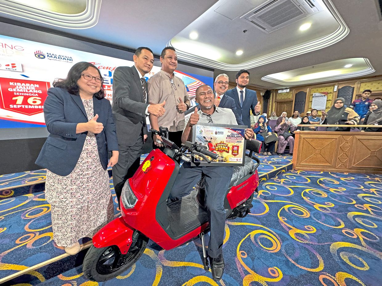 Rumaizi (second from right) presenting the ‘Fly the Jalur Gemilang’ grand prize of an electric motorcycle to Mohamad Ariff (on bike).