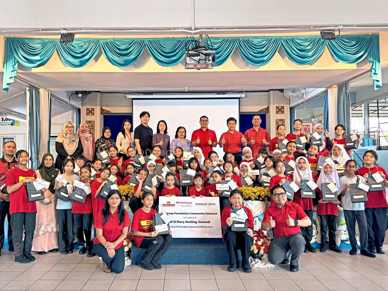 Shazman (back row, centre) and Su (beside Shazman), together with teams from the bank and Eyesight Optic, join students and school representatives for a group photo following the handover of prescription eyewear sponsored by AmGroup Foundation to 44 underprivileged students at SK St Mary, Kuching.