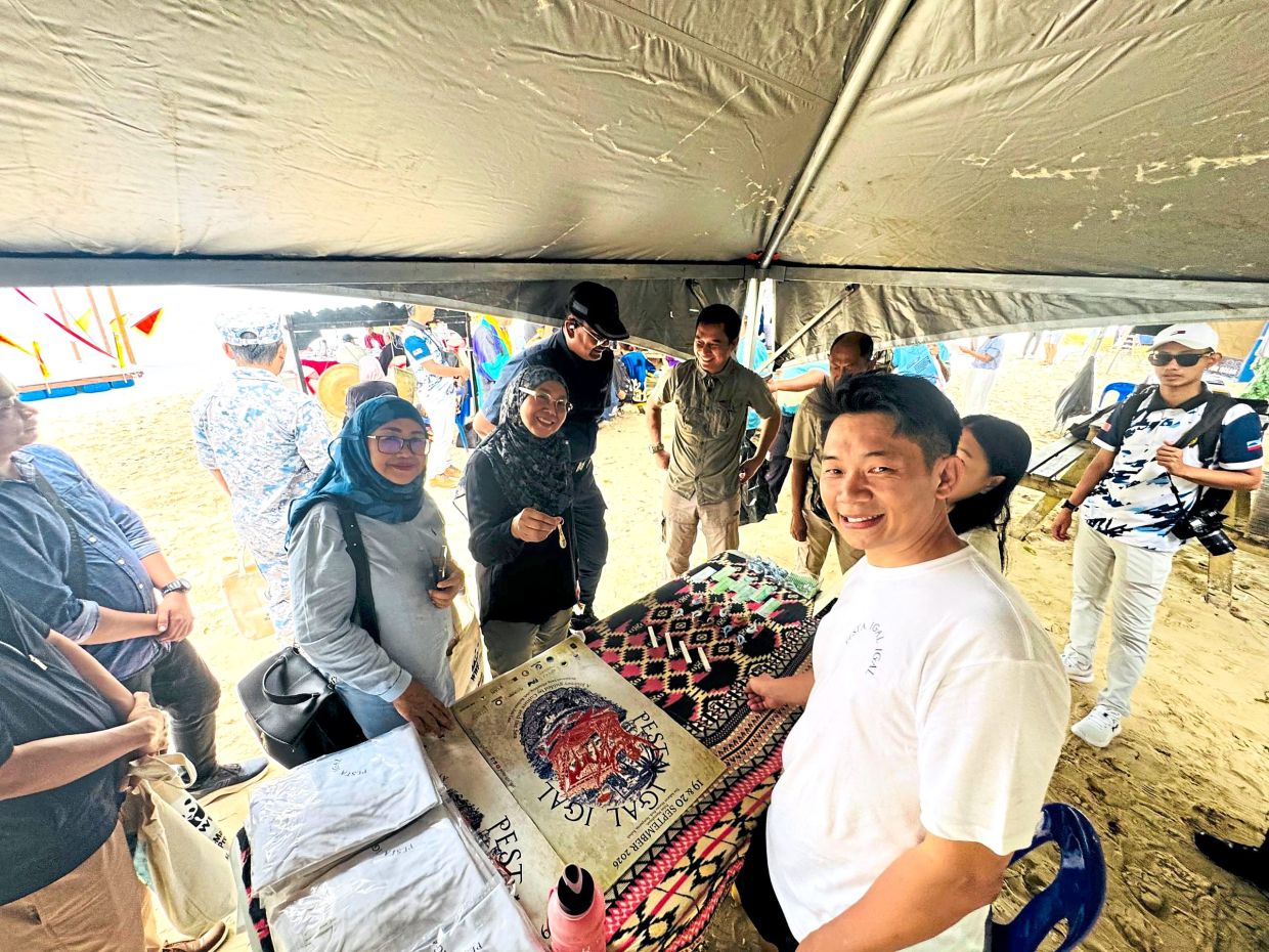 Ngui (right) showing off some of the exhibits at the festival to Rimi (centre, in black). — Kopsi