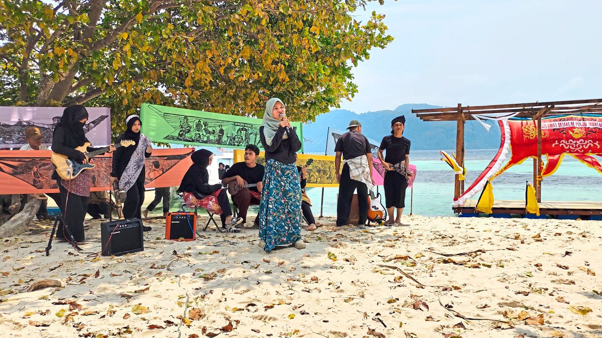 One of the members from the Borneo Komrad performing a heartfelt song, with Pangrok Sulap’s artwork, Masyarakat Adat Laut, in the background — IAN ASHLEY/Pangrok Sulap
