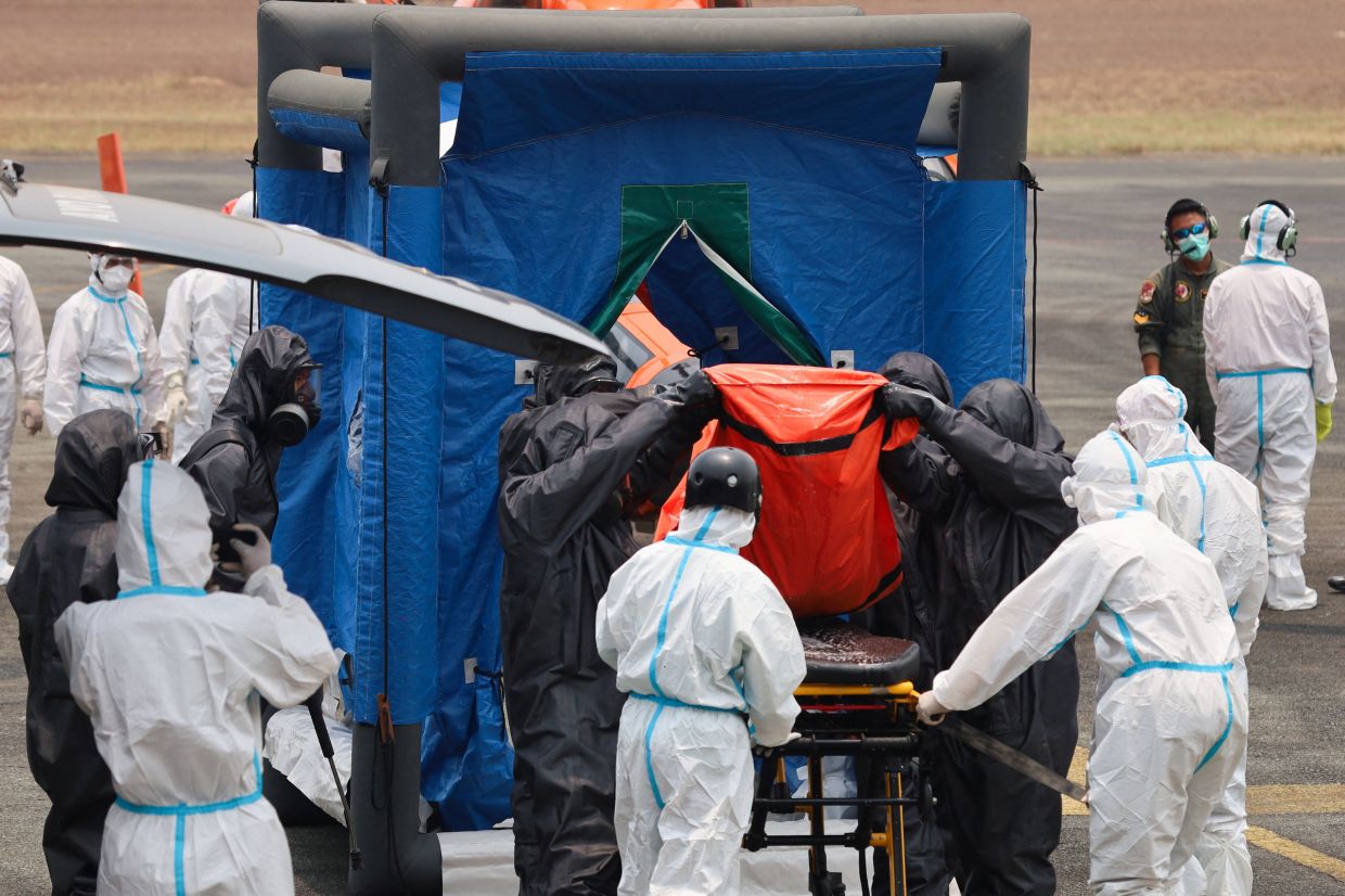 Rescuers in hazmat suits carry a body bag containing a victim recovered from the Virgo Transport 8 ferry, which capsized in the Java Sea while sailing from Surabaya in East Java to Banjarmasin in South Kalimantan, out of a disinfection chamber before the body is transported to a hospital for identification, upon arrival at Sjamsudin Noor Air Base in Banjarbaru, South Kalimantan province, Indonesia, on Friday, October 2, 2026. -- Photo: REUTERS/Abdulrahman Muda Sagala