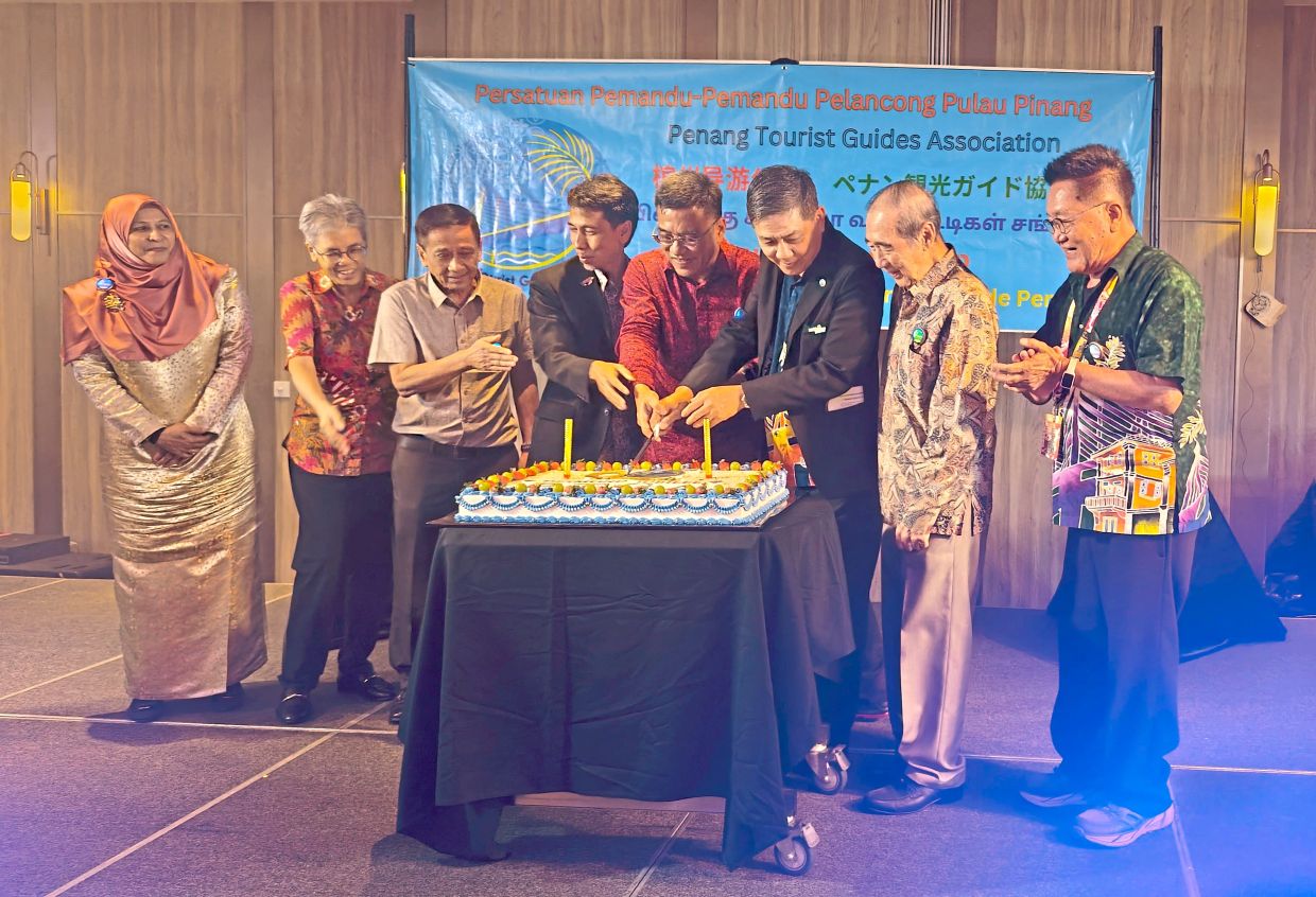 Wong (in red) flanked by Liang (third right) and Dr Annuar, cutting the cake during PTGA’s 60th anniversary celebration. — Handout