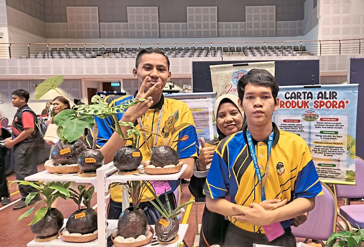 Young innovators: Qayyum Daniel (far left) and Muhammad Riezman (far right) with their teacher at their exhibition booth.