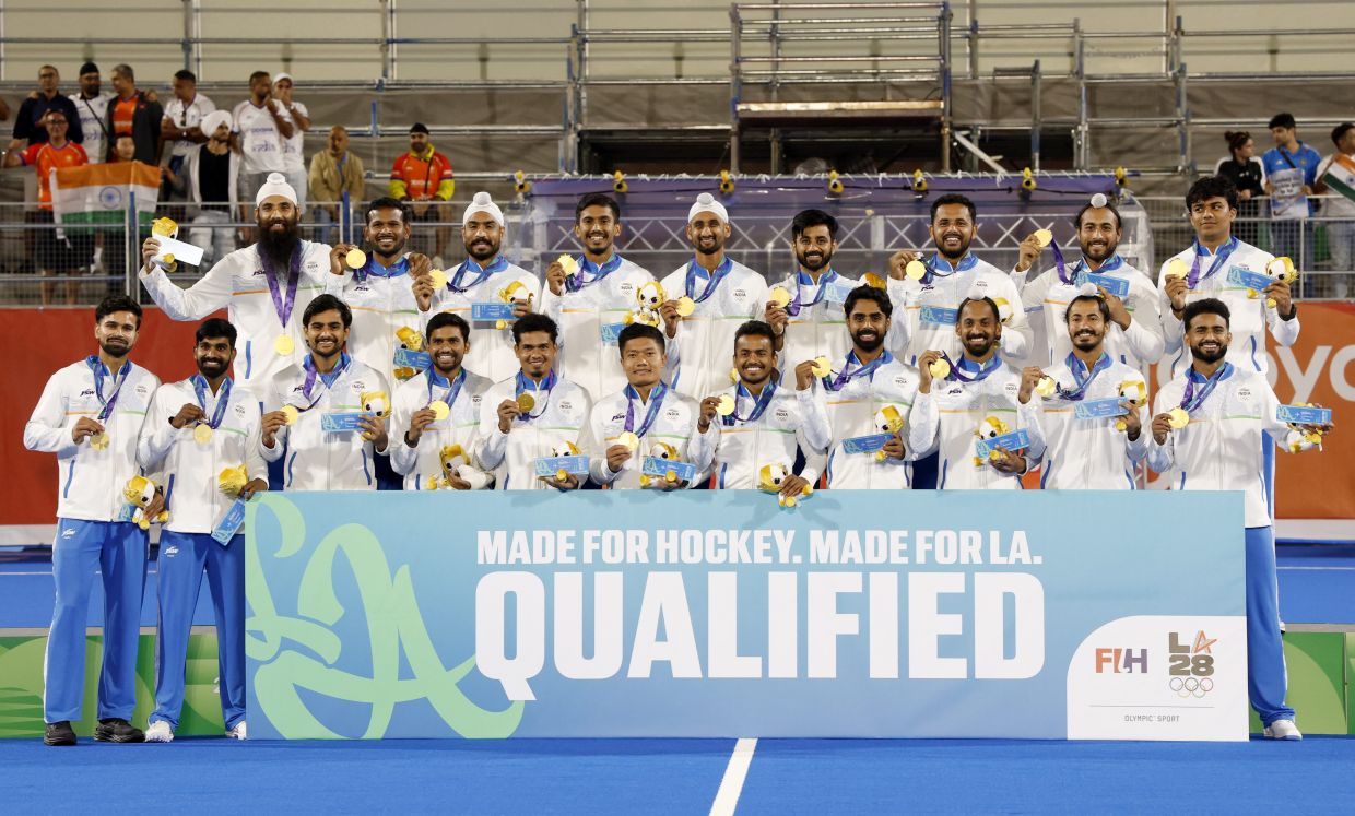 Asian Games - Aichi-Nagoya 2026 - Field Hockey - Men - Victory Ceremony - Gifu Prefectural Green Stadium, Kakamigahara, Japan - Saturday, October 3, 2026. The Indian hockey team, after winning the gold medal, poses with a banner after qualifying for the LA 2028 Summer Olympics. -- Photo: REUTERS/Manami Yamada