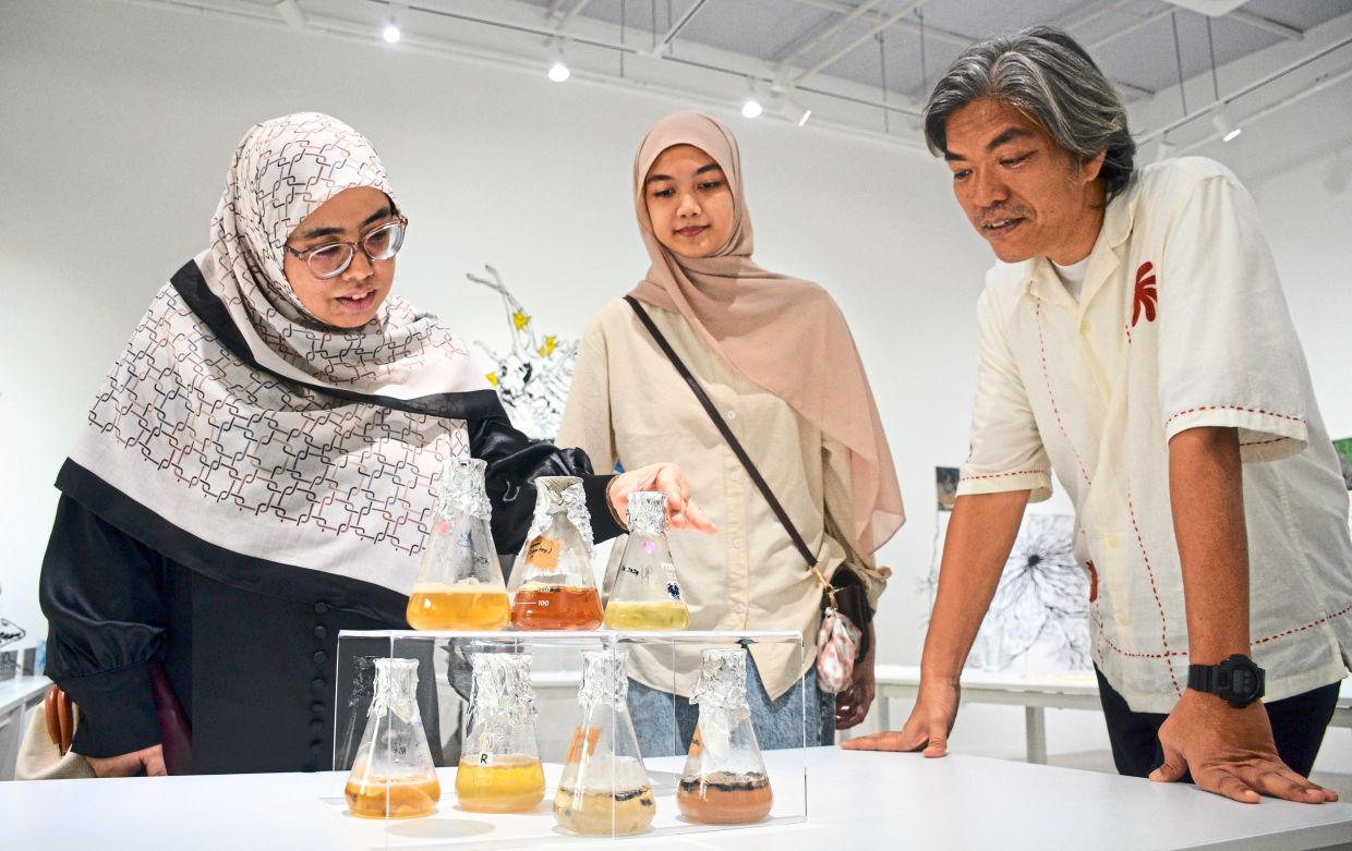 Rosnida (left) and a student, chatting with artist Hasanul (right) about some of the mycelia cultures on display at the 'Fruiting Bodies' exhibition. Photo: Jeremy Tan 