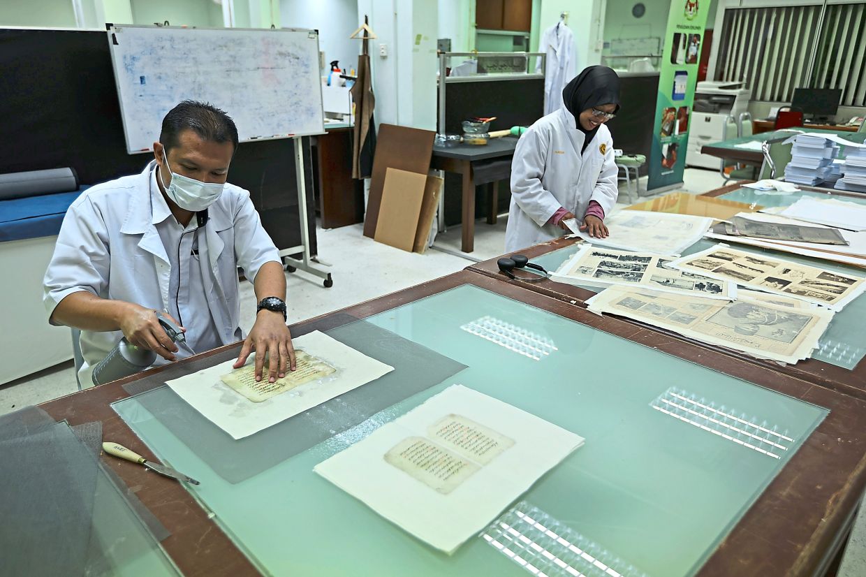 Archivists working to restore materials such as newspaper articles.