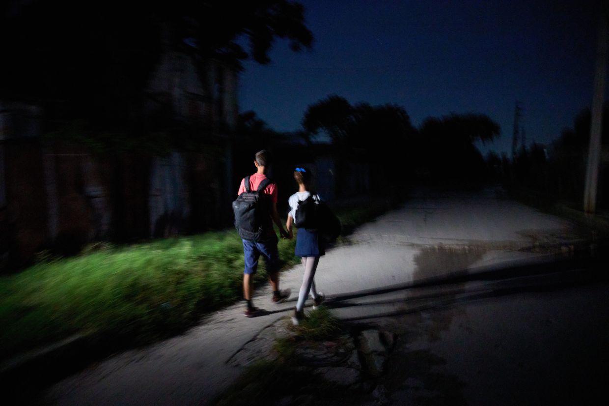 Ballet students walk during a blackout on their way to the National Ballet School in Havana, Cuba. Photo: AP