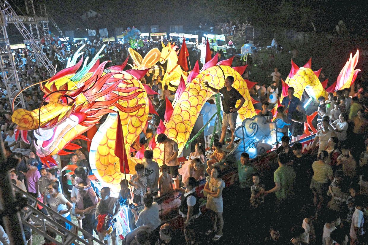 4. People gathering around a giant dragon lantern float in Hanoi, Vietnam. Lantern displays and colourful processions are among the festival’s most popular traditions, particularly among children. — AFP