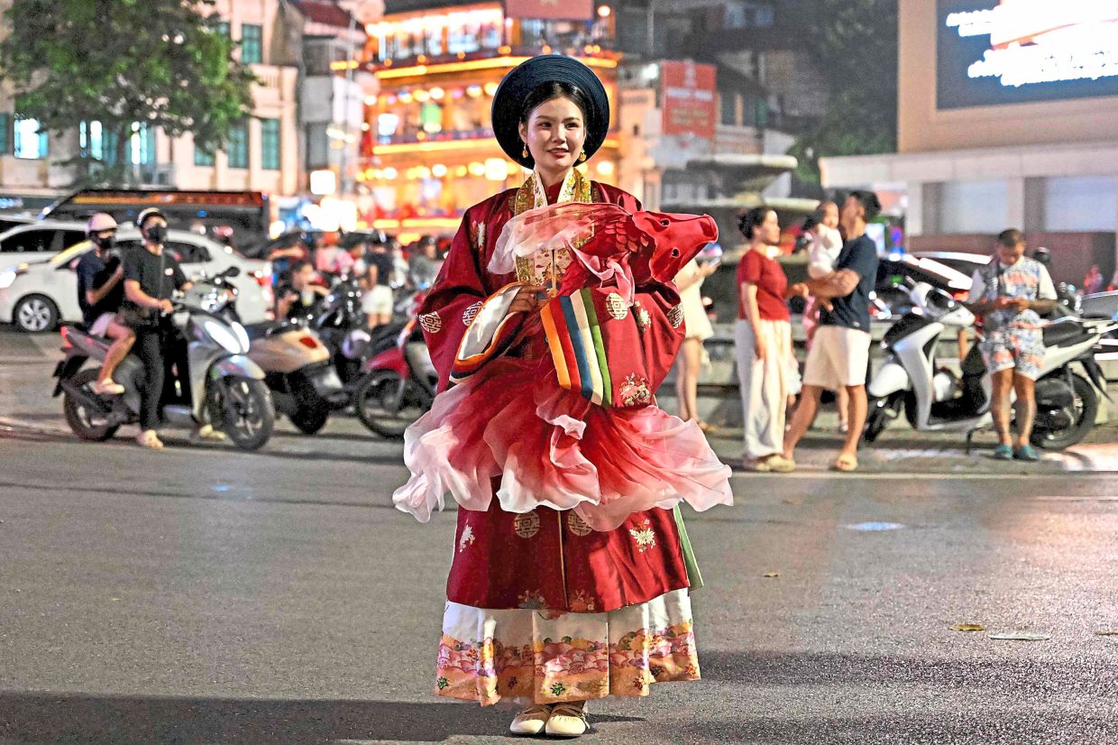 2. A young woman in traditional ethnic attire poses for photographs at Hoan Kiem Lake in Hanoi, Vietnam. Known locally as Tet Trung Thu, the festival centres on children, family togetherness and the autumn harvest. — AFP