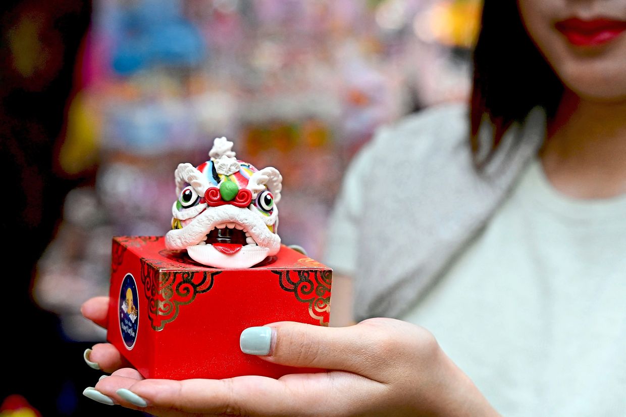 6. A woman displays a traditional Vietnamese ‘to he’ figurine shaped like a lion dance head at a stall in Hanoi’s Old Quarter. Made from rice flour, the colourful creations are a popular feature of Mid-Autumn Festival celebrations, particularly among children. — AFP