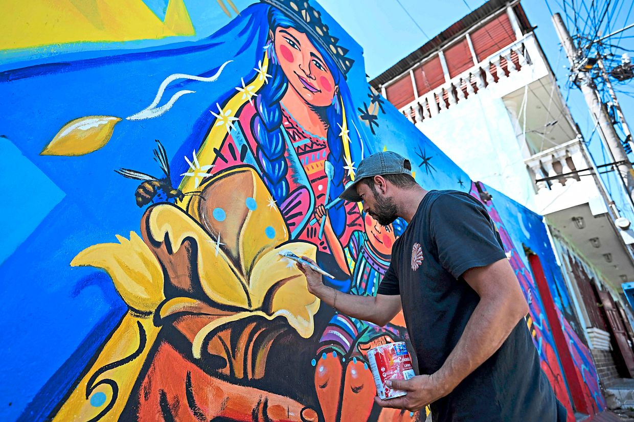 4. Guatemalan artist Luis Fernando Izquierdo retouches his mural of the Virgin Mary and child Jesus on a street in Santa Maria de Jesus, Guatemala. The mural is part of ‘A New Air for Santa Maria de Jesus’, an initiative to restore deteriorating spaces and strengthen the community’s identity through art. — AFP
