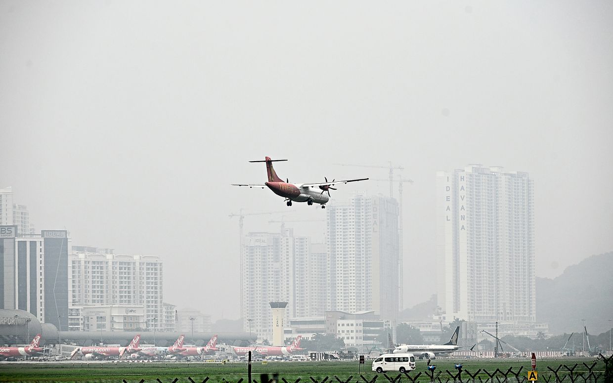 3. A passenger plane descends through hazy skies at Penang International Airport. Skies across the island and mainland turned visibly grey in September, with the highest API reading reaching 206. — Bernama