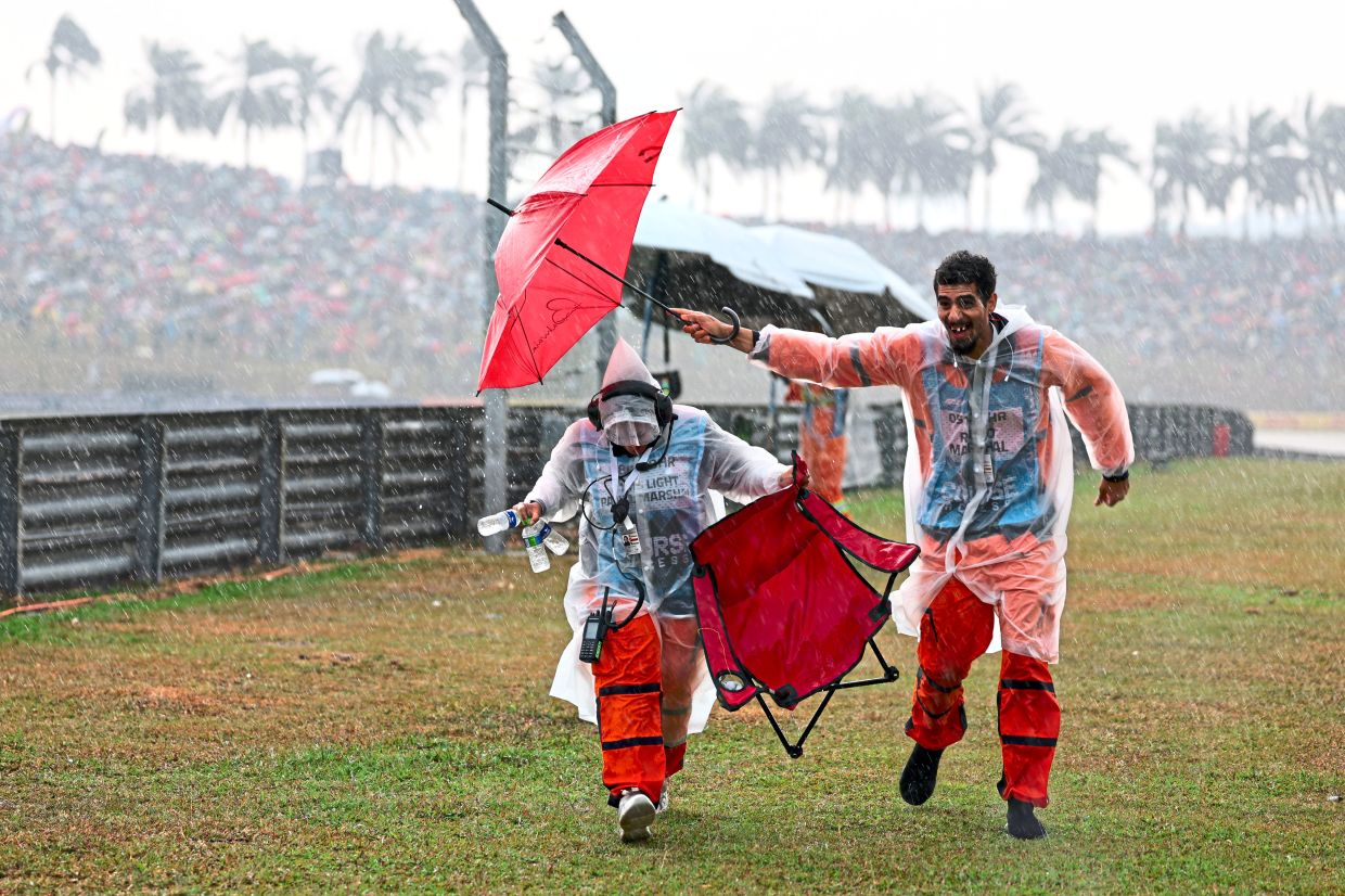 5. Track marshals make a dash for cover as heavy rain lashes Sepang. — GLENN GUAN/The Star