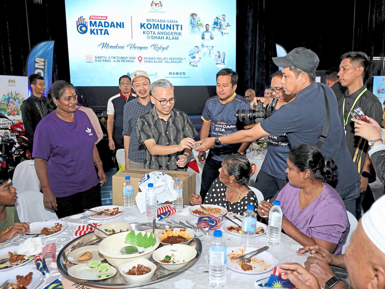 Fahmi (second from left), with Mohd Najwan on his left, giving away food baskets to residents.