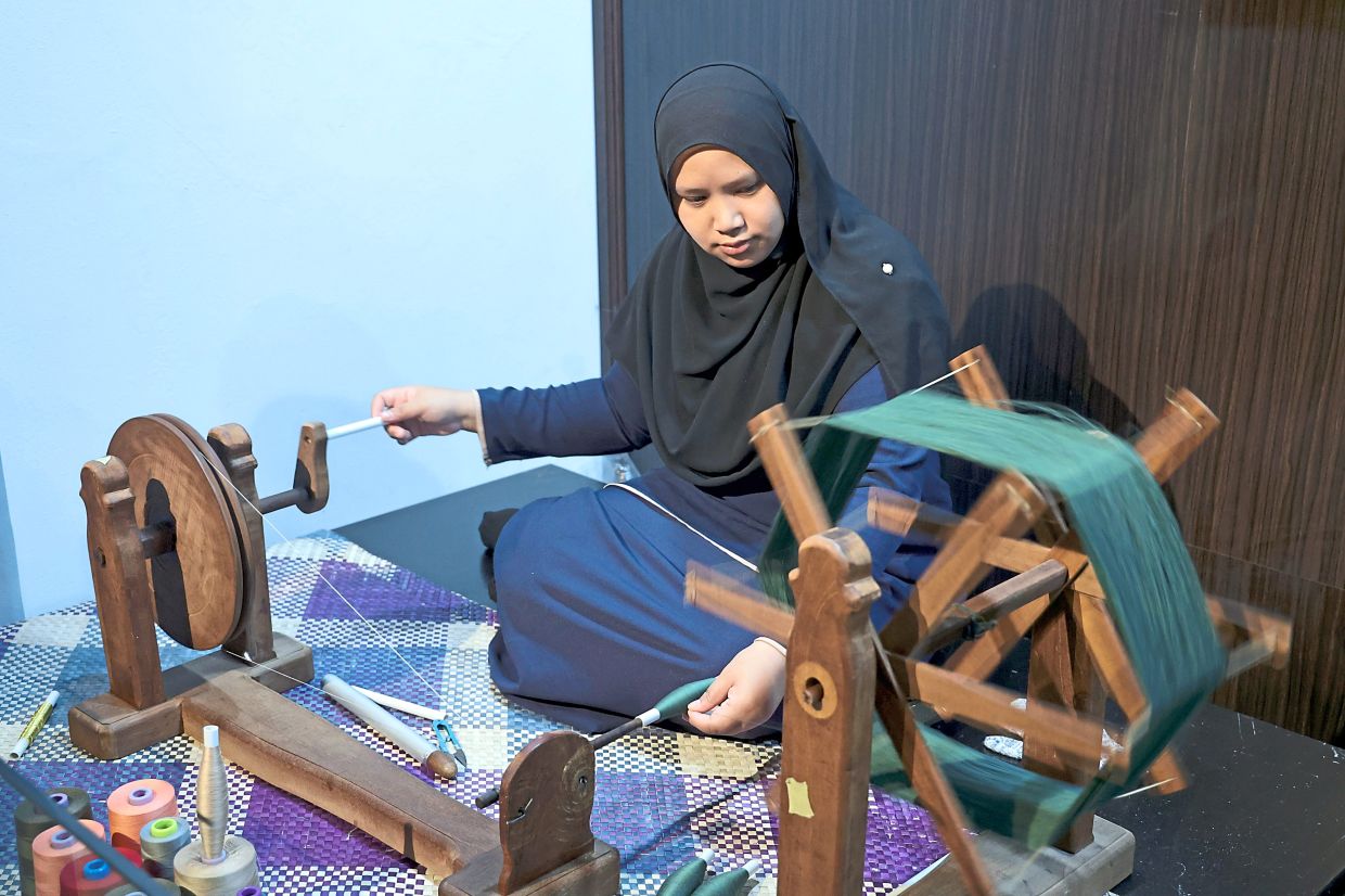 Siti Aisyah gently winding the thread into a roll, before beginning the process of weaving. 
