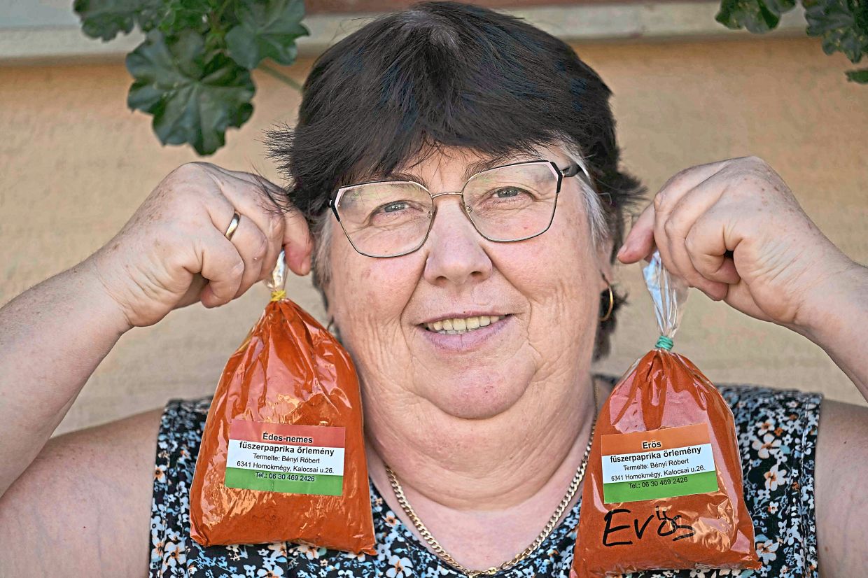 Farmer Rozsa Benyi holding up two packages of ground paprika at her home in Homokmegy. Paprika cultivation and the production of traditional paprika strings are still important in Hungary today.