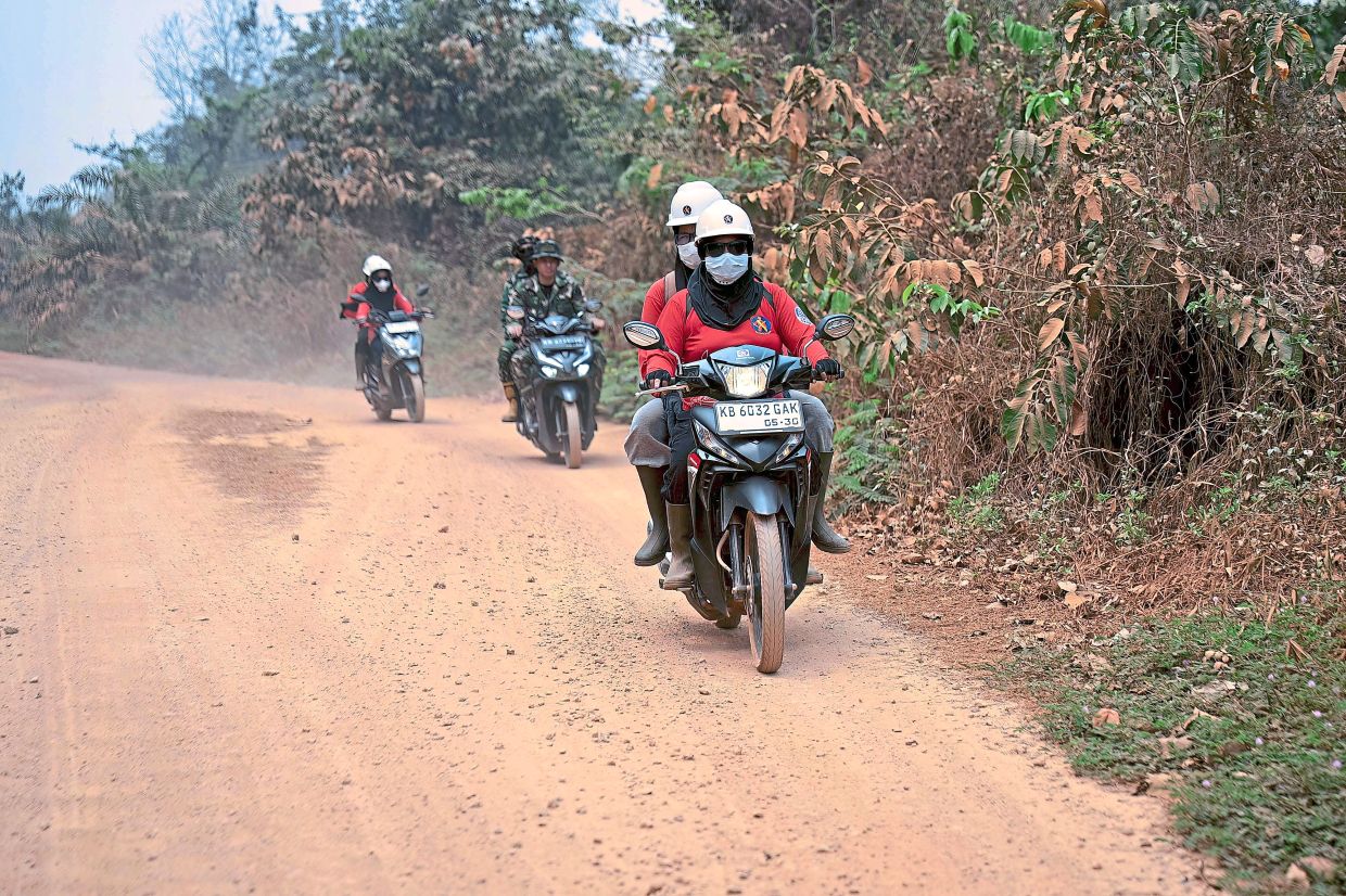 Members of the all-women TPoM volunteer firefighting team ride motorcycles as they patrol for flare-ups. Photo: Heribertus/AFP