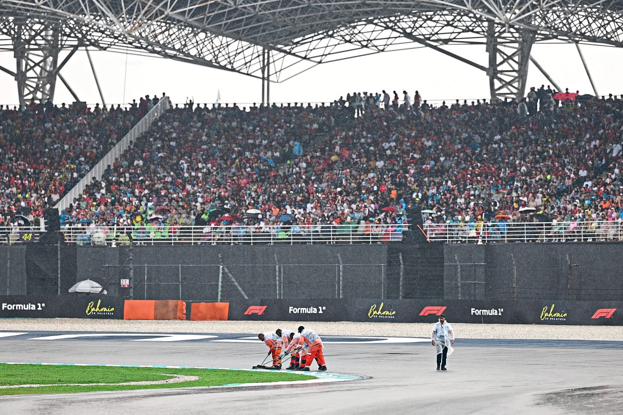 Marshals drying the track after a downpour which delayed the start of the race at SIC.