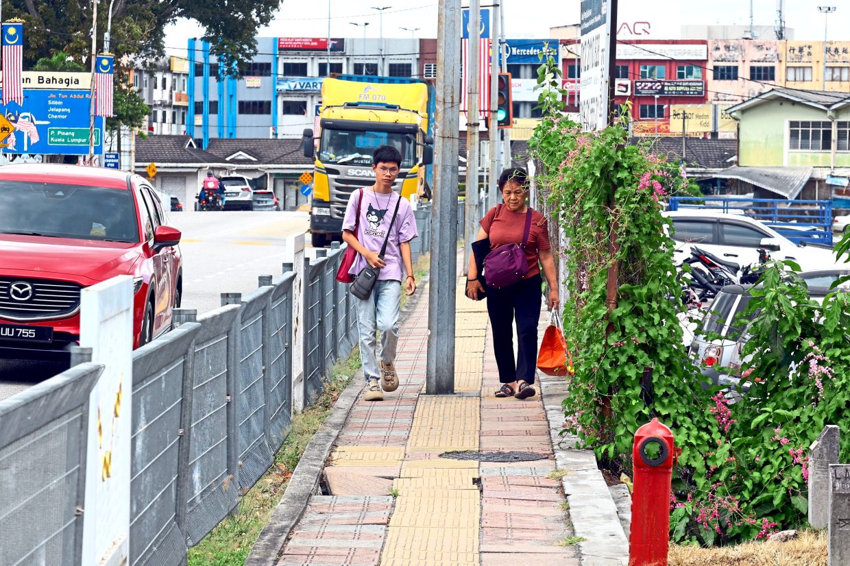 Pedestrians have to watch their step to avoid holes and broken pavement along a walkway near the railway station.