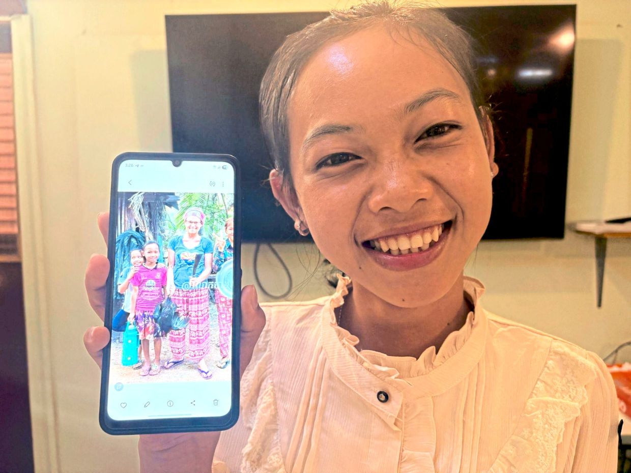 Tem Sreyloch showing a photo of herself as a child in her village.