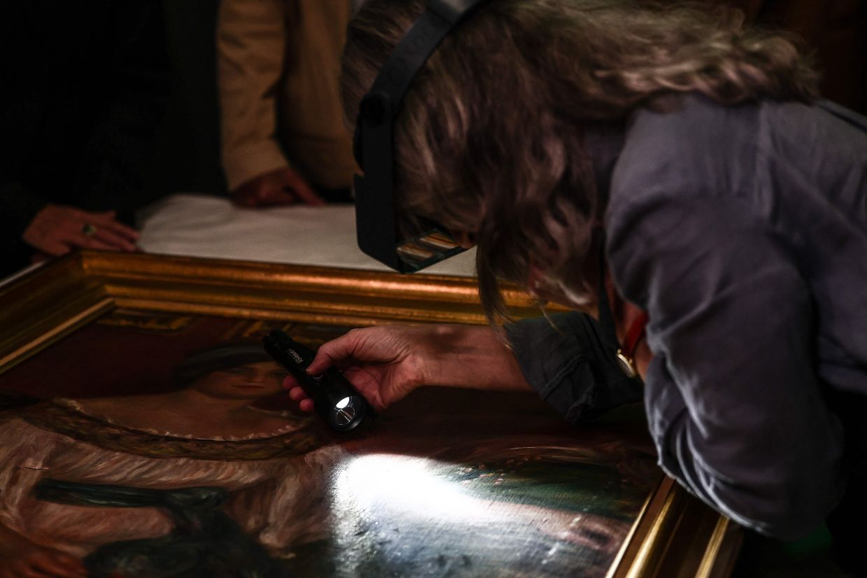 A restorer reveals to the media, a damage on the 'Portrait Of Madame Colonna Romano' painting by Renoir. Photo: AFP 